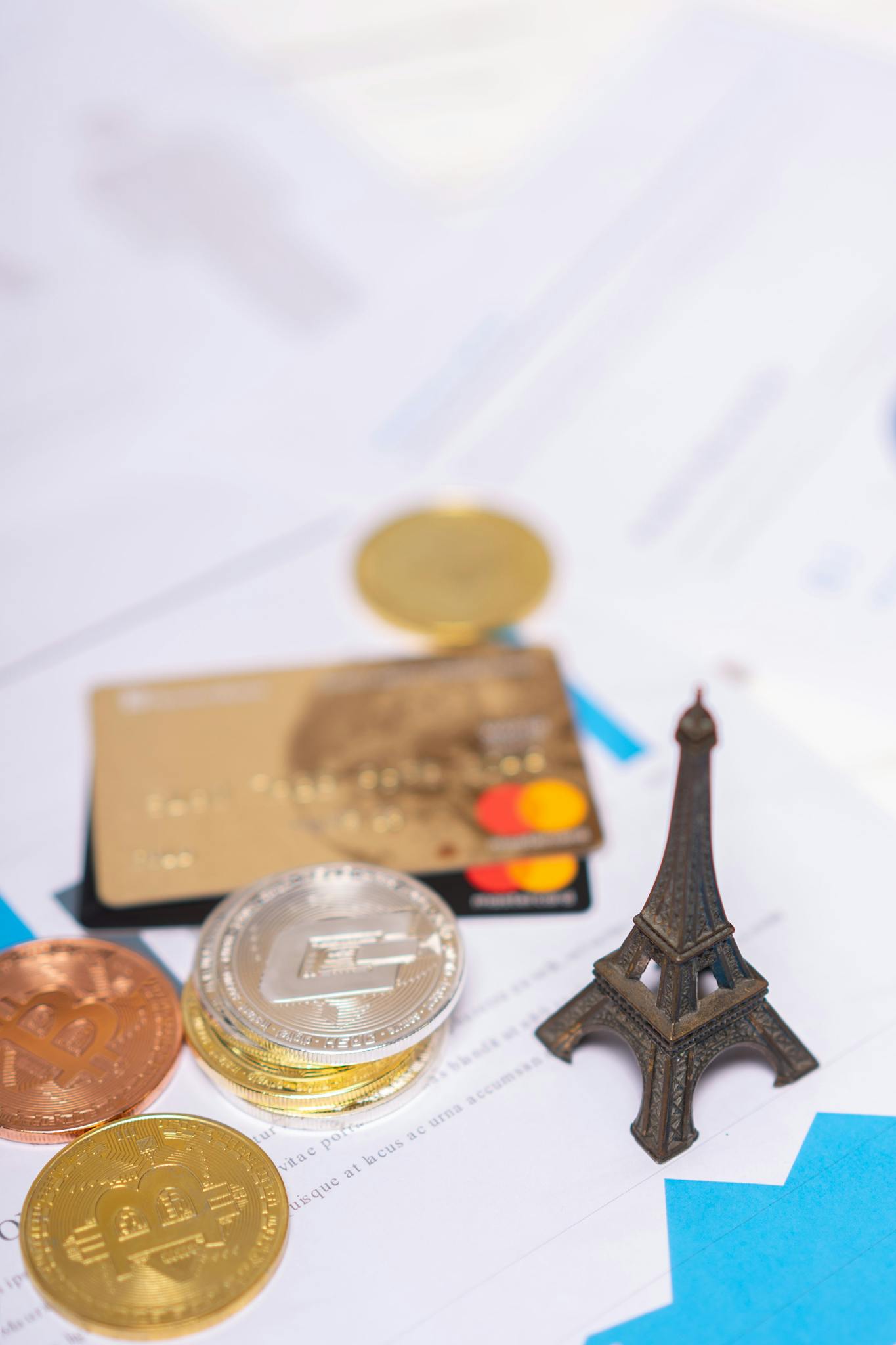 Miniature Eiffel Tower with bank cards and coins on documents, symbolizing finance and travel.